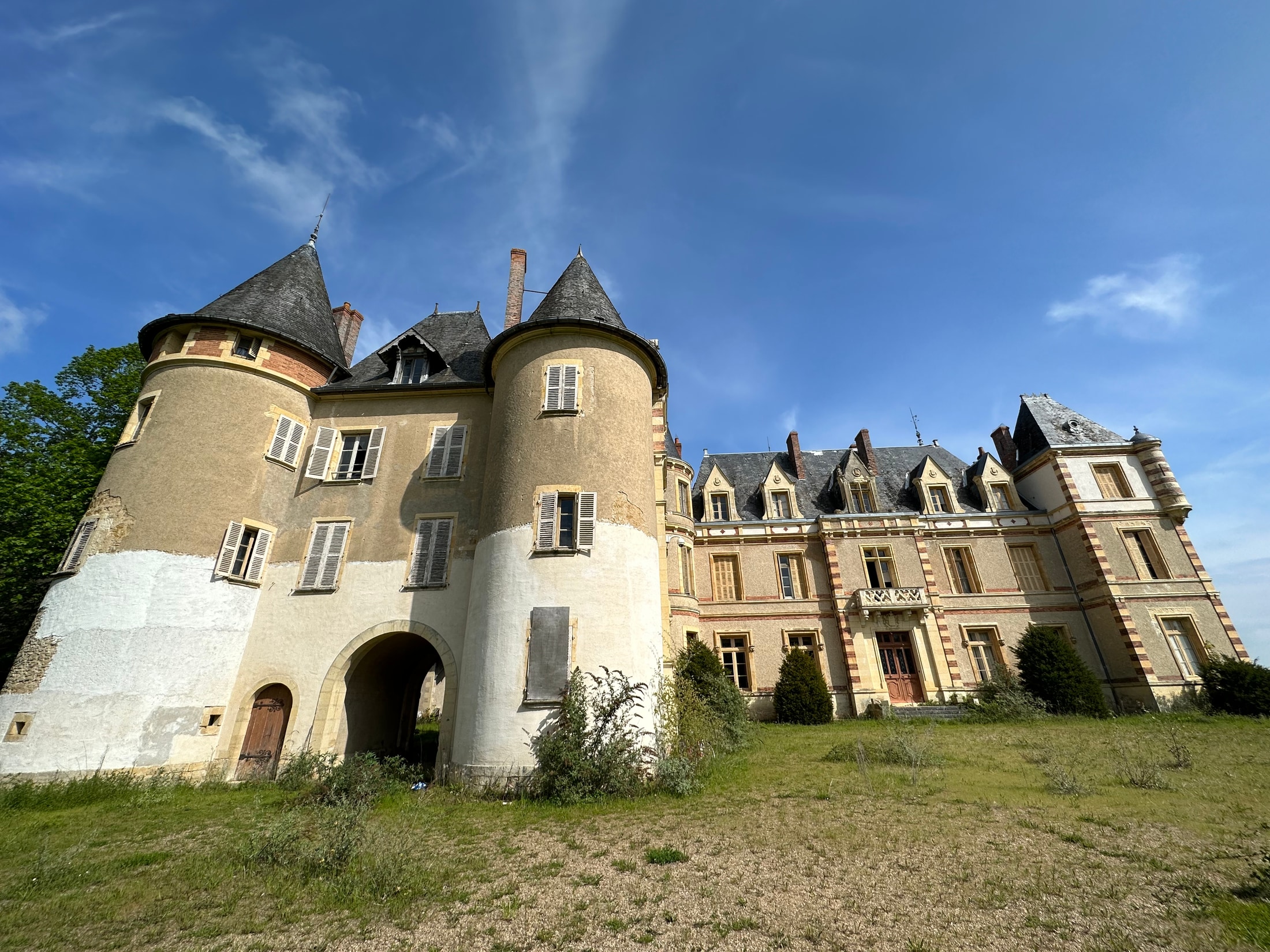 Außenansicht des Château mit Türmen und verwildertem Gelände