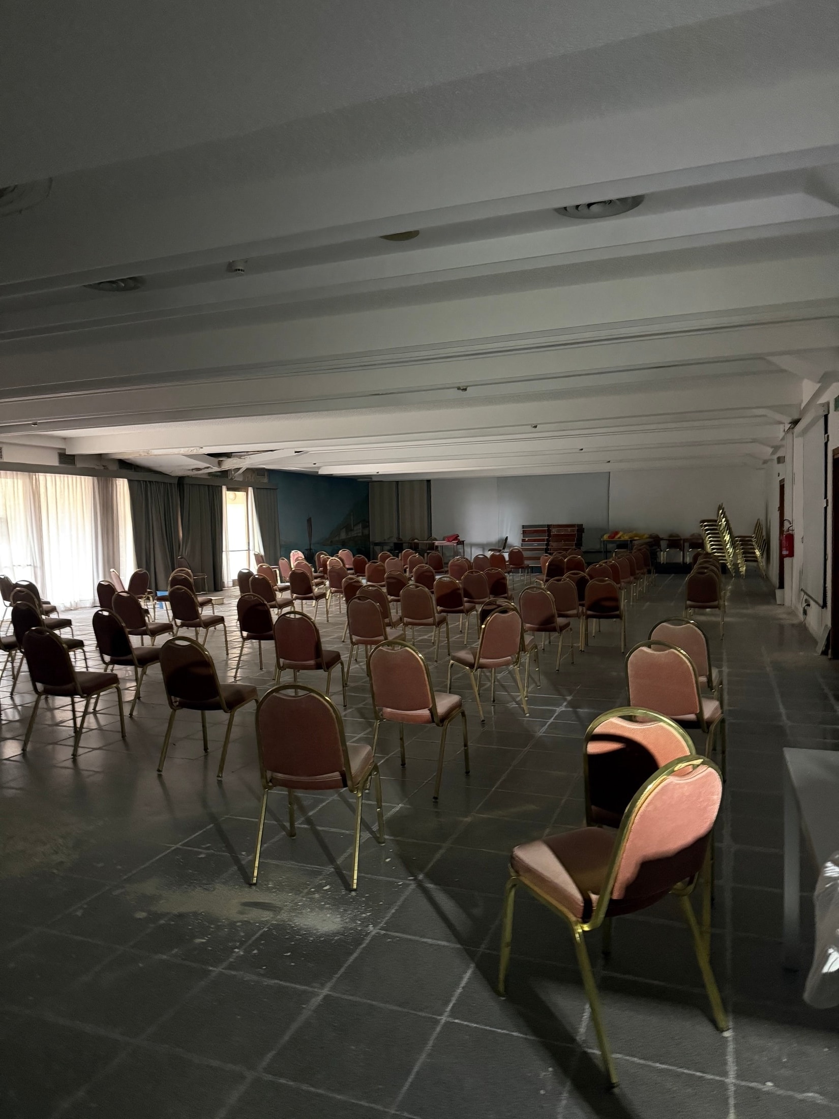 Ehemaliger Saal mit Reihen aus Stühlen und gedämpftem Licht