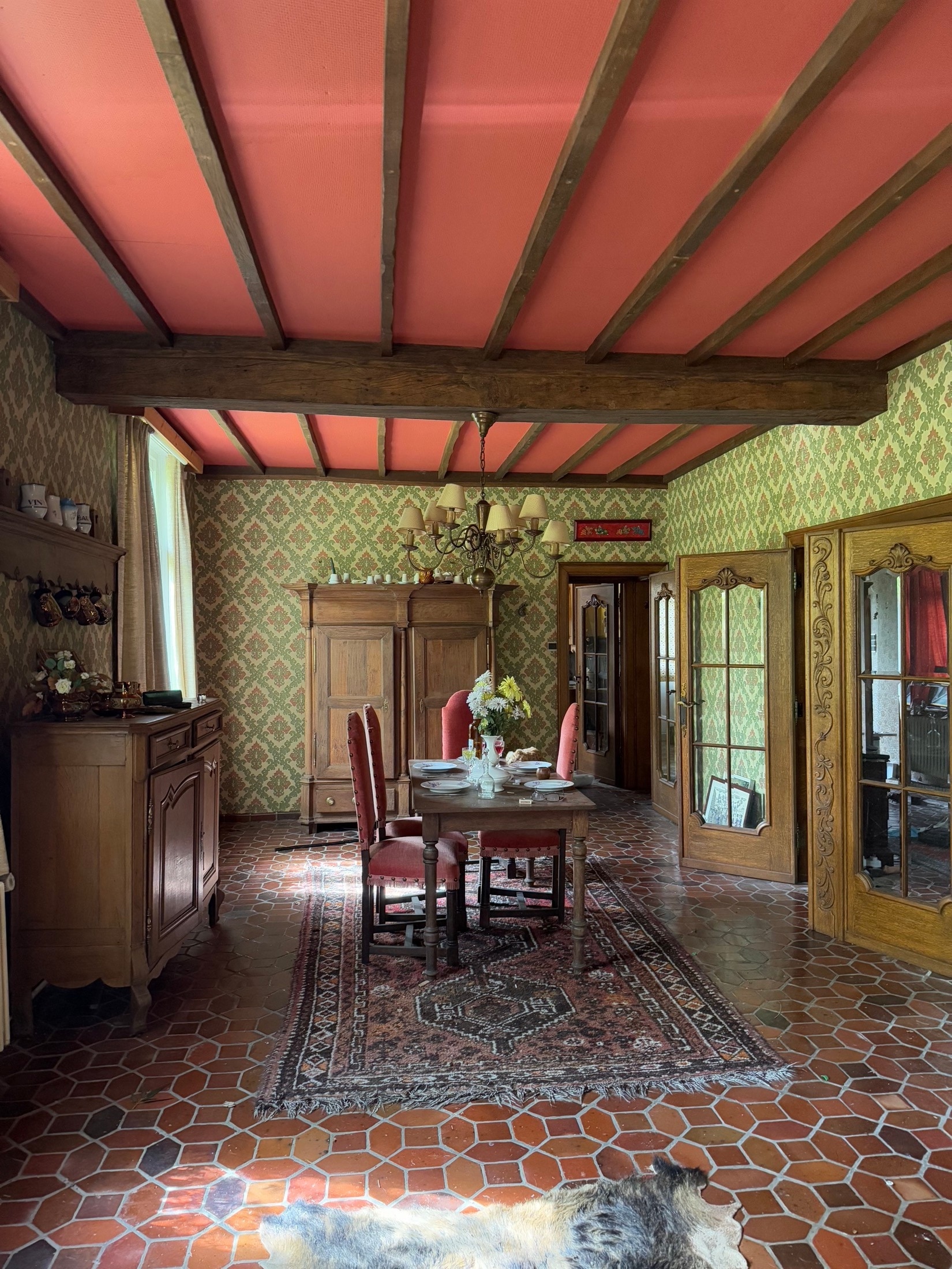 Verlassenes Esszimmer mit Holzbalken, Teppich und gedecktem Tisch